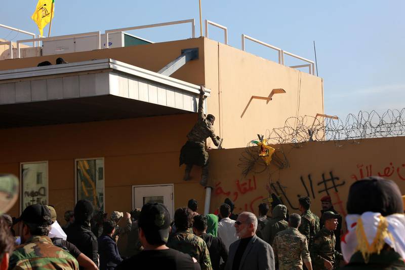 Members of the Popular Mobilisation Forces and their supporters attack the entrance of the US embassy in Baghdad.  EPA