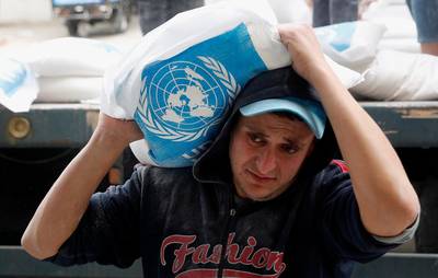 A Palestinian worker carries sacks of flour distributed by the United Nations Relief and Works Agency (UNRWA) for poor refugee families, at the Sheikh Redwan neighborhood of Gaza City, Tuesday, March 31, 2020. The United Nations has resumed food deliveries to thousands of impoverished families in the Gaza Strip after a three-week delay caused by fears of the coronavirus. UNRWA, provides staples like flour, rice, oil and canned foods to roughly half of Gazaâ€™s 2 million people. (AP Photo/Adel Hana)