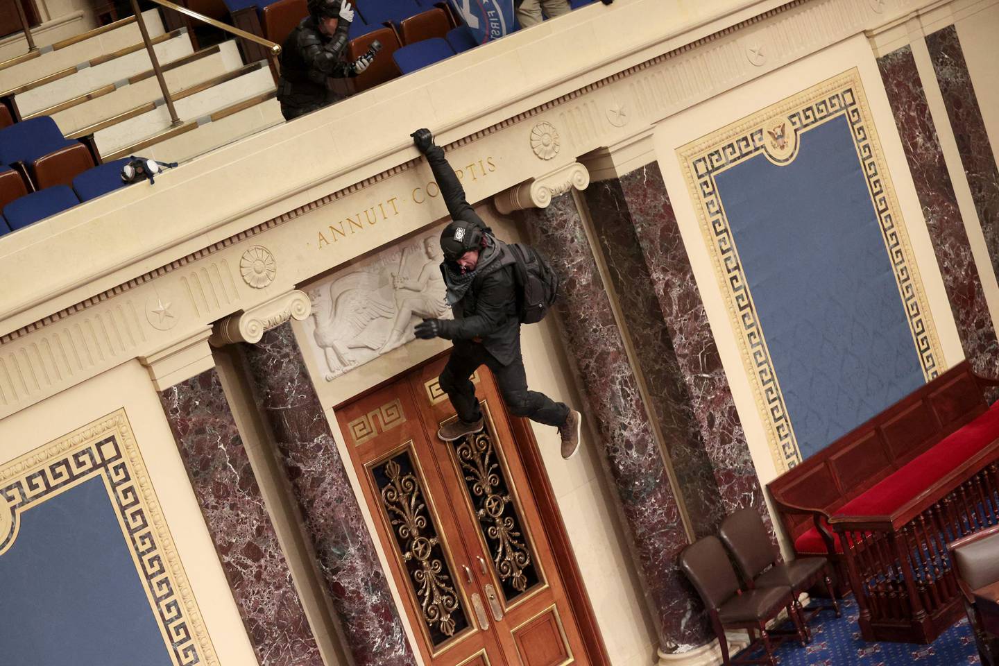 Josiah Colt from Idaho hangs from the balcony in the Senate Chamber in the US Capitol in Washington when Trump supporters stormed the Capitol, on January 6, 2021. AFP