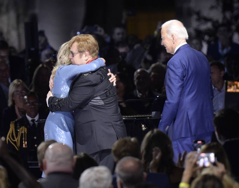 Joe Biden looks on as Jill Biden embraces Elton John. UPI
