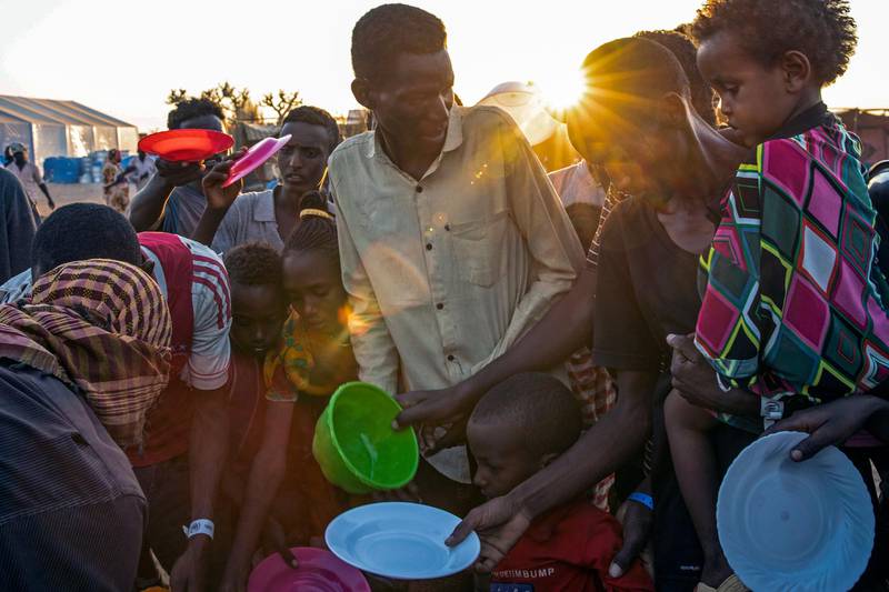 Refugees who fled the conflict in Ethiopia's Tigray region wait to get cooked rice served by Sudanese local volunteers at Um Rakuba refugee camp in Qadarif. AP