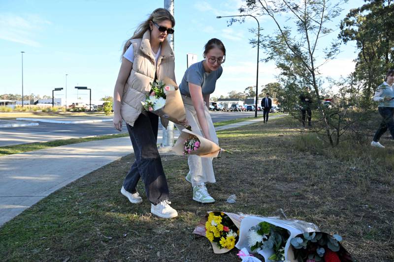 Women lay flowers on the side the road, about 500 metres from the site of the bus crash. AFP