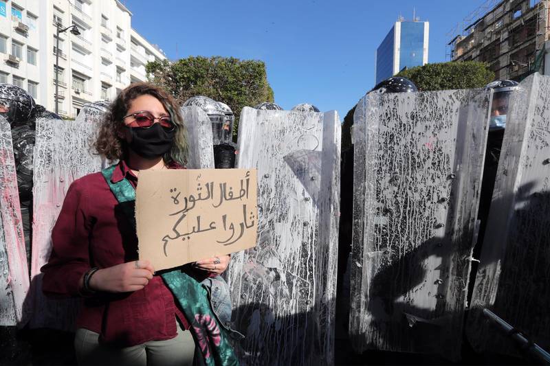 A protester holds a placard reading in Arabic 'Children of the revolution revolted against you' in front of anti-riot policemen during a demonstration in Tunis. EPA