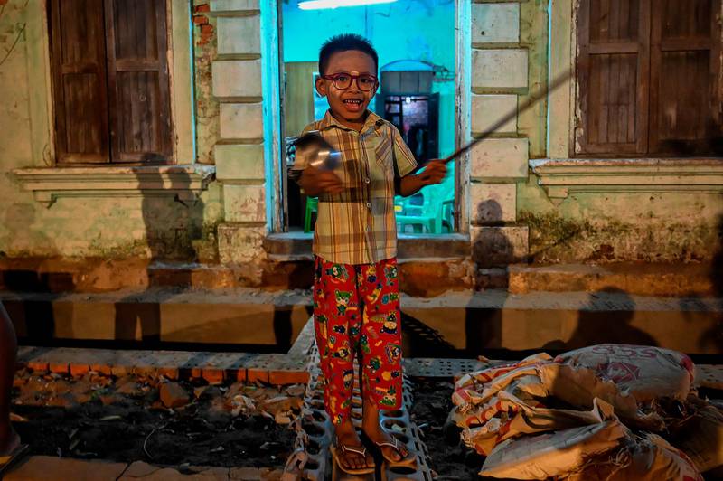 A child hits a plate with a pair of scissors to make noise after calls for protest went out on social media in Yangon. AFP