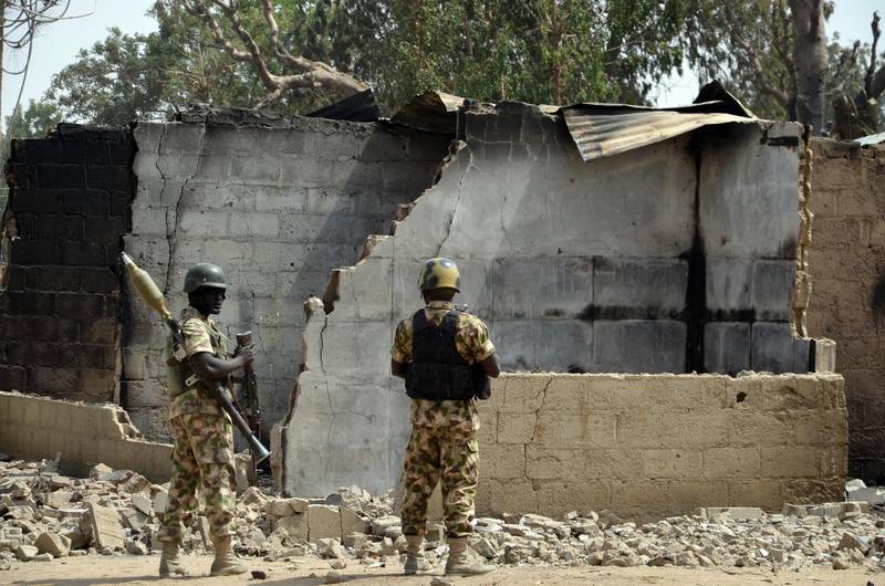 Soldiers looks at burnt house on February 4, 2016 during a visit to the village of Dalori village, some 12 kilometres from Borno state capital Maiduguri, northeastern Nigeria, after an attack by Boko Haram insurgents on the village left at least 85 people dead on January 30, 2016. - At least 85 people died when Boko Haram insurgents stormed and torched a village on January 30 near the restive northeast Nigerian city of Maiduguri, a state commissioner said on February 1, 2016. Boko Haram, which seeks a hardline Islamic state in northern Nigeria, has killed some 17,000 people and forced more than 2.6 million others to flee their homes since 2009. (Photo by STRINGER / AFP)