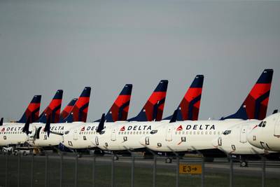 FILE - In this April 1, 2020 file photo, several dozen mothballed Delta Air Lines jets are parked at Kansas City International Airport in Kansas City, Mo. The skies are clearing up a bit for airlines as states ease lockdown measures and travelers slowly return to airport check-in lines. More airlines are restoring flights to their schedules and investors have taken note, driving up shares for the major airlines after a staggering decline.  (AP Photo/Charlie Riedel, File)