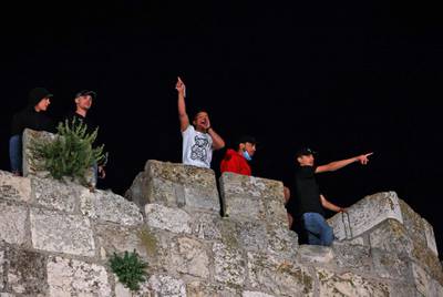 Palestinian youths watch clashes between protesters and Israeli security forces in Jerusalem. Israel said six police officers were injured. AFP