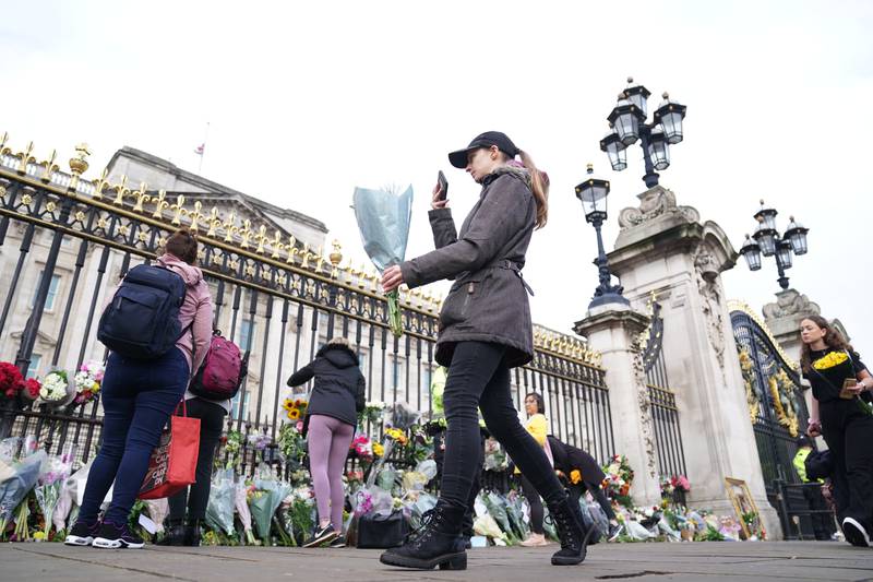 A woman lays flowers at Buckingham Palace in London following the death of Queen Elizabeth II on Thursday. Photo: PA