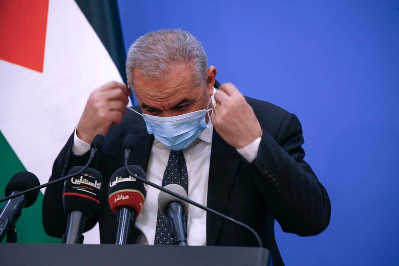 Palestinian Prime Minister Mohammad Shtayyeh puts on a protective mask after holding a press conference in Ramallah.  AFP