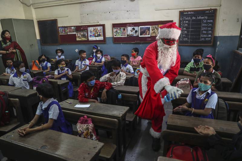 A man dressed as Santa Claus gives sanitiser to pupils as they attend school in Mumbai. AP