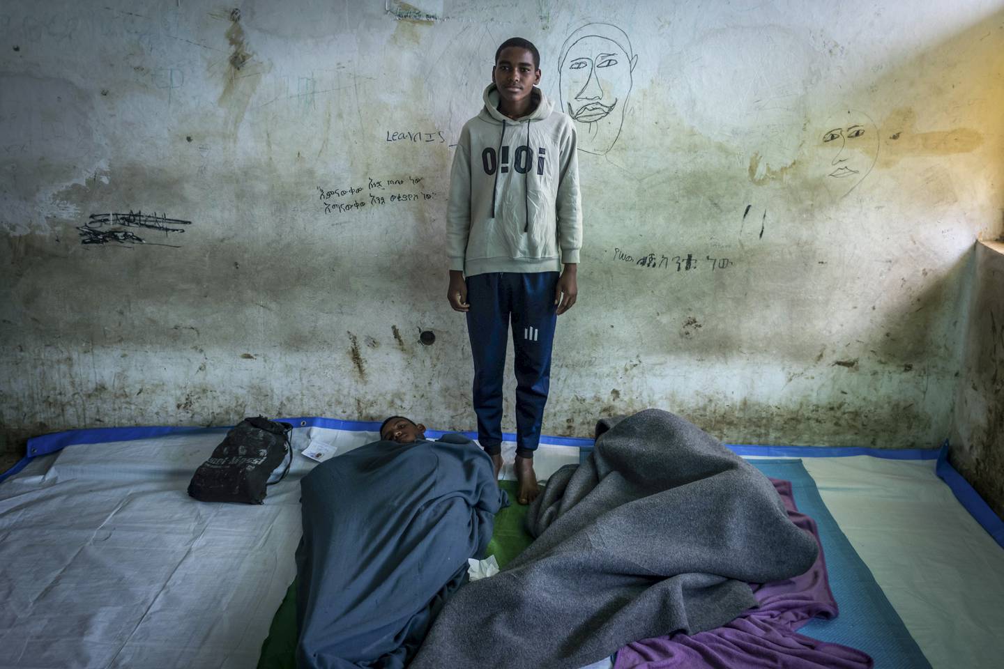 Mulu Adugna, 18 years old, poses for a photo in the room where he sleeps at a center for the internally-displaced in Debark, in the Amhara region of northern Ethiopia Friday, Aug.  27, 2021. AP