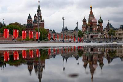 The Kremlin Wall with Spasskaya Tower, left, and St. Basil's Cathedral are reflected in a rainwater on the almost empty Bolshoy Moskvoretsky bridge decorated with red flags prior to celebrating Victory Day in Moscow, Russia, Wednesday, May 6, 2020. Russian authorities have decided to reopen all industrial plants and construction sites in the capital starting next week, citing a stable rate of the coronavirus. President Vladimir Putin says it will be up to officials in other regions of the country to determine when it's possible to ease lockdown measures in place since the end of March. (AP Photo/Alexander Zemlianichenko)