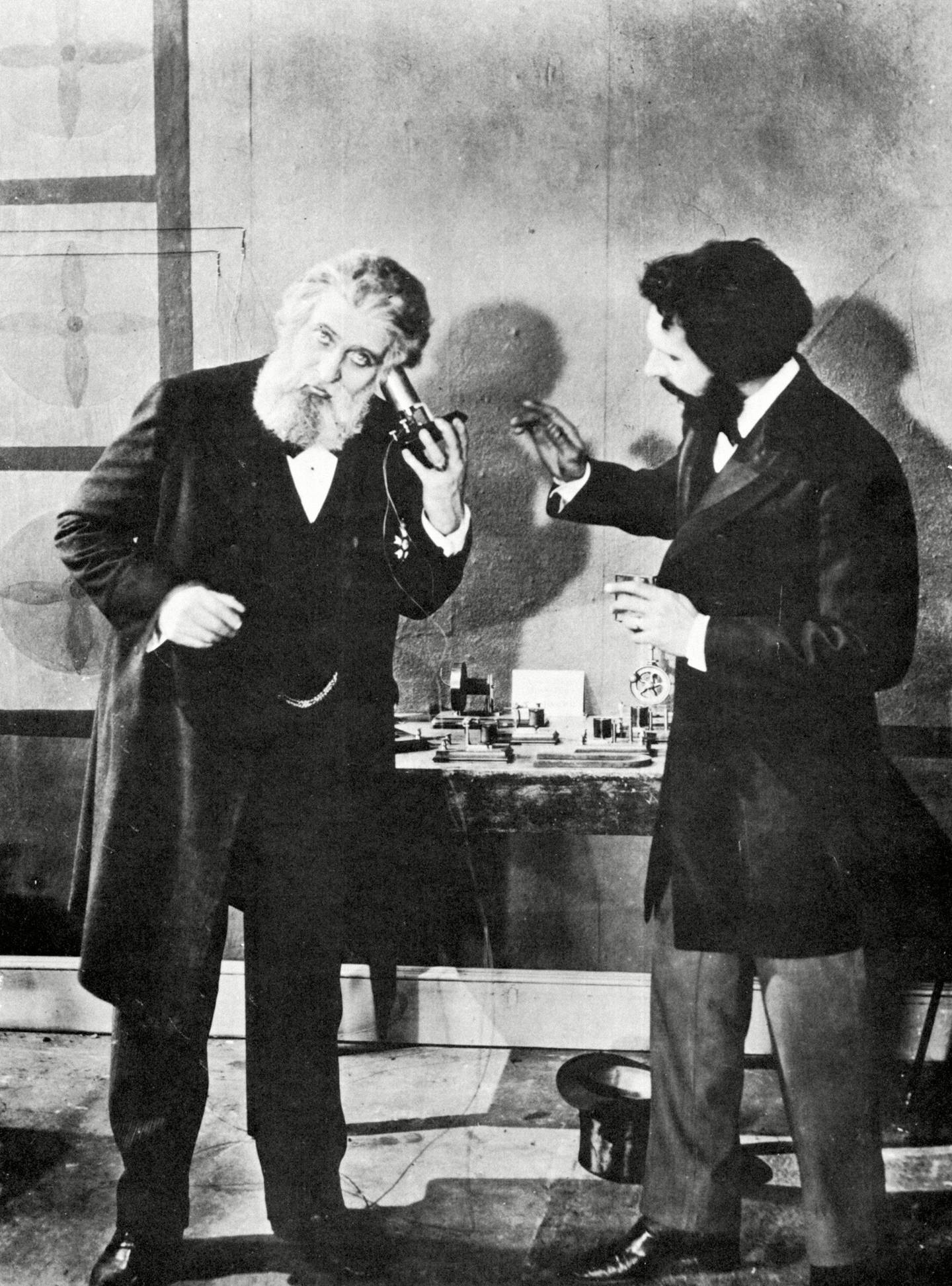 Inventor Alexander Graham Bell, right, instructs Brazilian Emperor Dom Pedro II on the use of his telephone receiver during the Philadelphia Centennial Exposition, 1876.