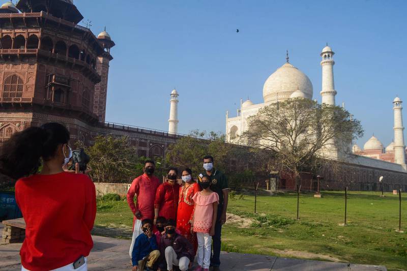Visitors wearing facemasks as a preventive measure against the COVID-19 coronavirus have their picture taken outside Taj Mahal following its closure in Agra.   AFP