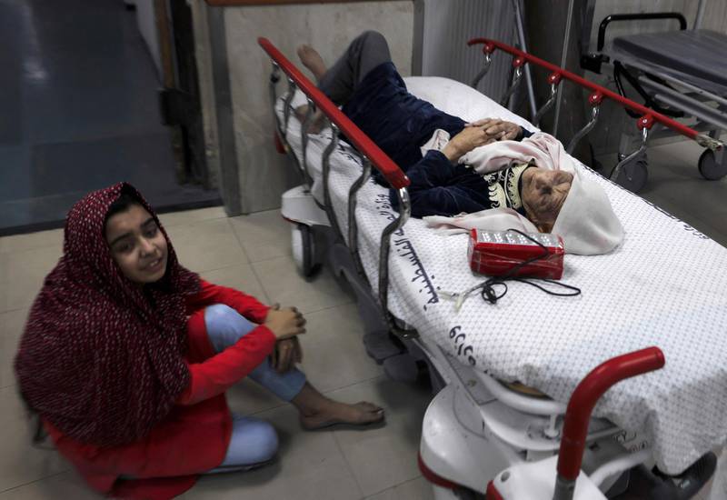 A Palestinian girl sits on the floor next to her wounded grandmother at Al Shifa Hospital, after an Israeli air strike on Al Shati Refugee Camp in Gaza City. AFP
