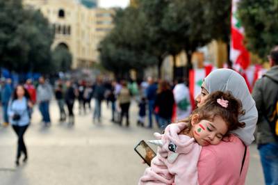 A woman carries her daughter during a protest in downtown Beirut.  EPA