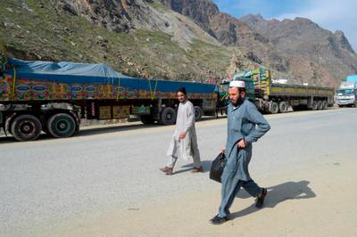 Men walk past Afghan's trucks parked along a road near the closed Pakistan-Afghanistan border amid concerns over the spread of the COVID-19 novel coronavirus, in Torkham some 54 kms from Peshahwar.   AFP