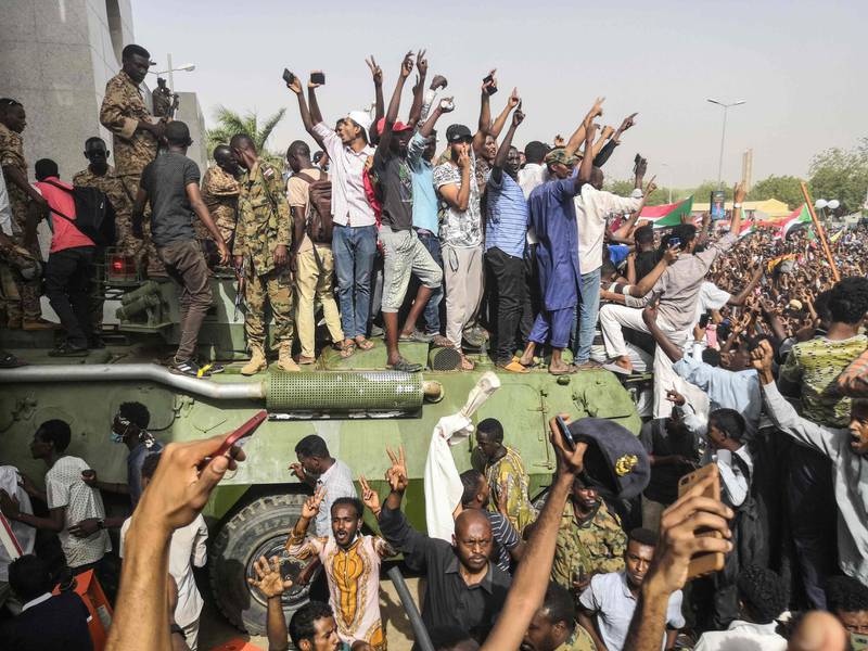 Sudanese anti-regime demonstrators stand on an armoured military vehicle. AFP
