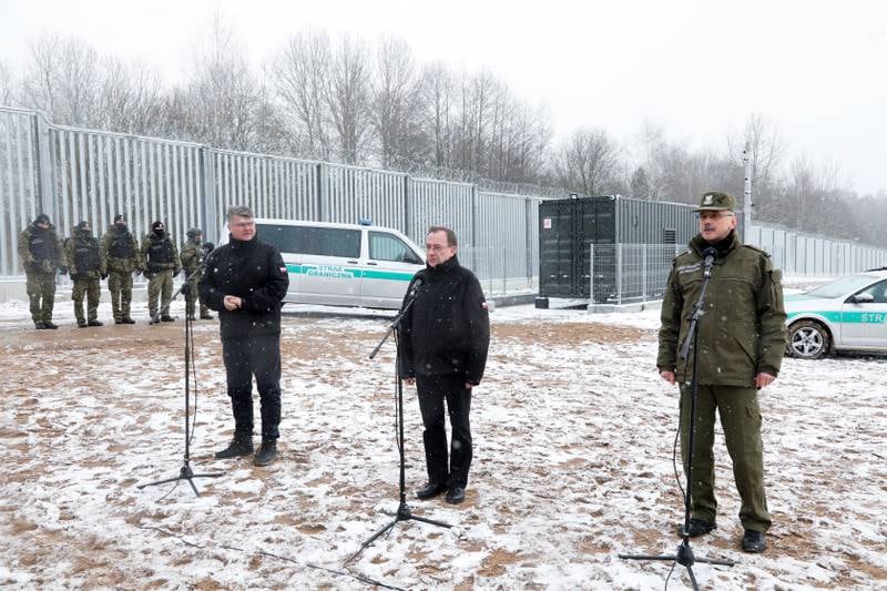 Minister of the Interior Mariusz Kaminski, centre, and Deputy Minister Maciej Wasik, left, at the Polish-Belarusian border to announce the completion of works on the first section of an electronic barrier. EPA