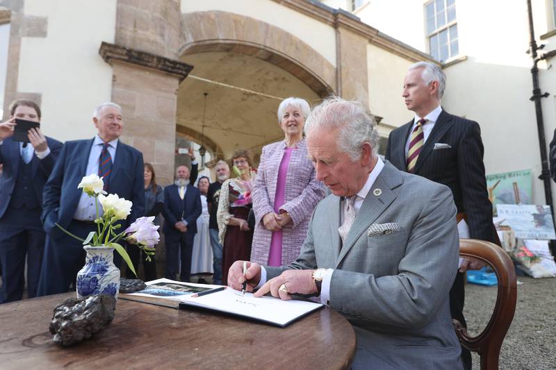 The Prince of Wales signs the visitors' book at Lissan House, Cookstown, during a visit to meet community groups. PA