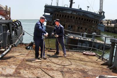 Russian Navy sailors of the Black Sea Fleet prepare to raise a sunken Ukrainian warship at the sea port, in Mariupol. AP