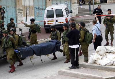 Israeli soldiers carry the body of one of two Palestinians shot in the West Bank city of Hebron on March 24, 2016. Abed Al Hashlamoun / EPA