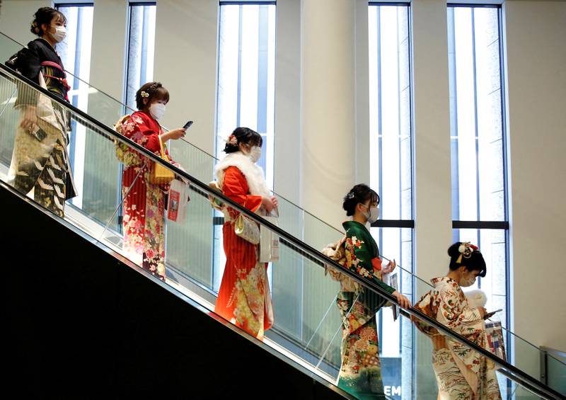 Women wearing kimonos and protective masks ride on an escalator in Tokyo. Reuters