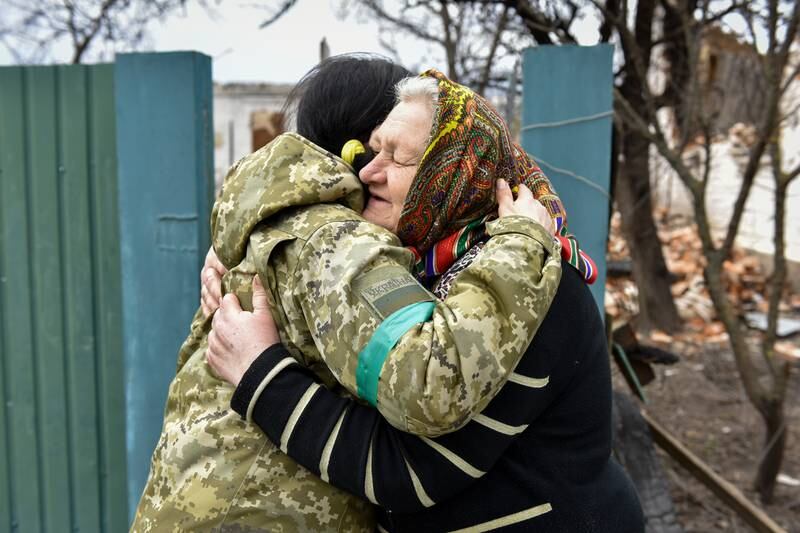 Sixty-two-year-old Luba hugs a Ukrainian servicewoman in Andriivka. EPA