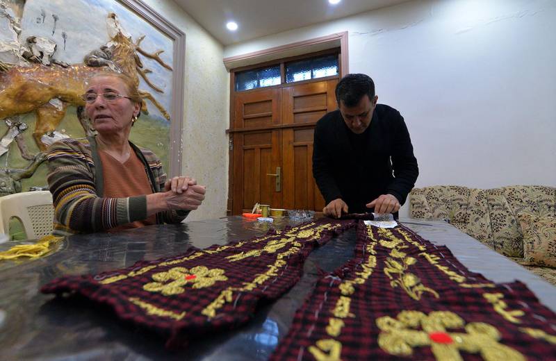 Iraqi priest Ammar Yaqo looks on as Karjiya Baqtar embroiders a precious prayer shawl using golden thread, to gift to Pope Francis during his upcoming visit to her Iraqi hometown Qaraqosh. AFP