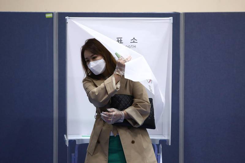 A South Korean woman wears a mask and plastic gloves to cast her vote in the Parliamentary election. Getty