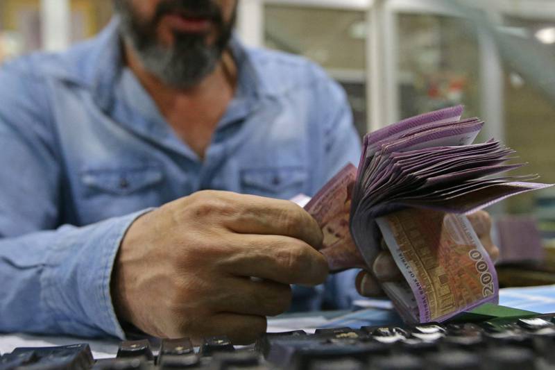 An employee counts Syrian banknotes at the Commercial Bank of Syria in Damascus.  AFP