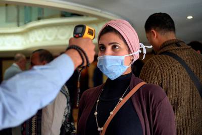 A woman wearing a protective health mask has her body temperature measured at a river boat in Egypt's southern city of Luxor on March 8, 2020. AFP