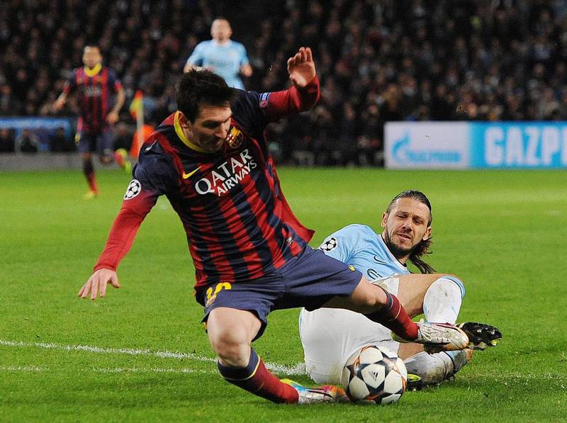 Barcelona's Lionel Messi, left, is fouled in the penalty box by Manchester City's Martin Demichelis during their UEFA Champions League round of 16 first leg match at the Etihad Stadium on February 18, 2014. Peter Powell / EPA
