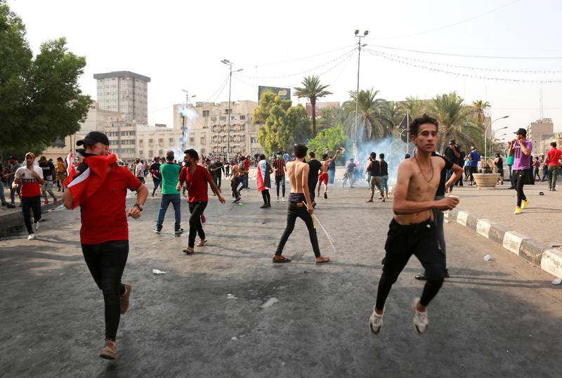 Iraqi protesters run for cover amid tear gas fired by policemen during a demonstration at Tahrir Square, central Baghdad.  EPA