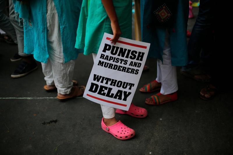 FILE - In this April 15, 2018 file photo, an Indian protestor stands with a placard during a protest against two recently reported rape cases as they gather near the Indian parliament in New Delhi, India. Indian police on Saturday, May 5, arrested 14 people suspected of kidnapping, raping and burning to death a teenage girl, the latest in rising crimes against women in India despite toughening of laws. Responding to widespread outrage over the recent rape and killings of young girls and other attacks on children, India's government last month approved the death penalty for people convicted of raping children under age 12. (AP Photo/Oinam Anand)