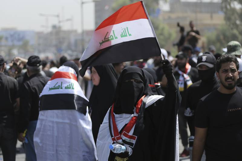 A veiled woman protester holds an Iraqi flag as people gather near the Green Zone area, in Baghdad. AP