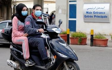 People wearing face masks ride on a motorbike outside Rafik Hariri hospital, where Lebanon's first coronavirus case is being quarantined, in Beirut, Lebanon. REUTERS