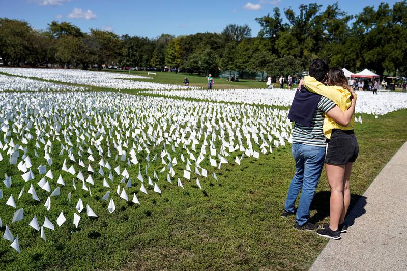 Two people hug as they look at the thousands of white flags. Reuters