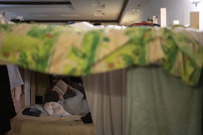 A woman reads a book as she lays on a bed in the shelter. AP