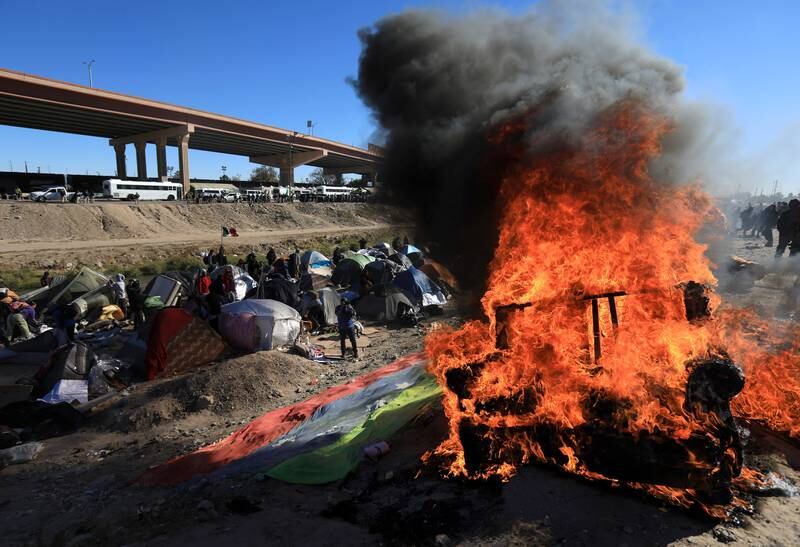 Belongings burn as Mexican authorities attempt to enforce an eviction at a migrant encampment, in Ciudad Juarez, Mexico, 27 November 2022.  Migrants and authorities clashed at the banks of the Rio Grande River where migrants had set up tents near the border with the United States.   EPA / Luis Torres
