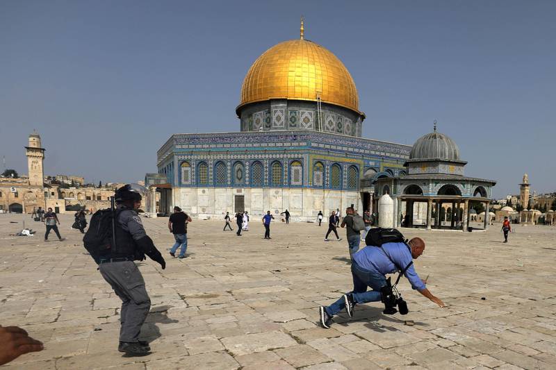 A camera operator falls as an Israeli police officer runs after him during clashes with Palestinians at the compound that houses Al Aqsa Mosque. Reuters