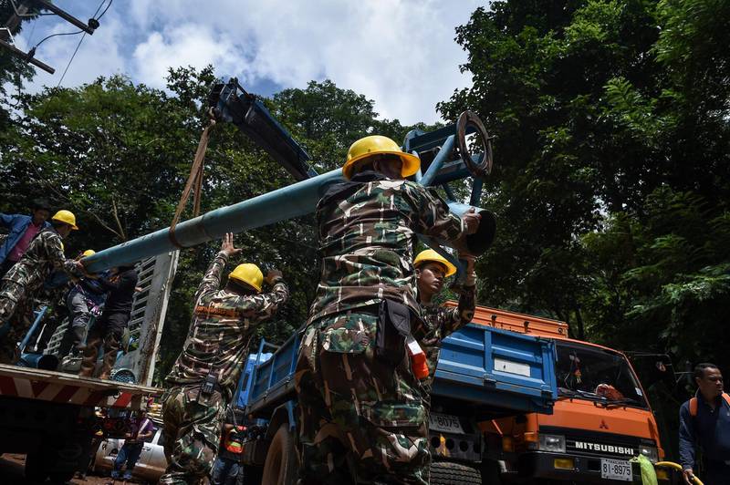 Technicians lift water pumps to the drilling site near Tham Luang cave. Lillian Suwanrumpha / AFP