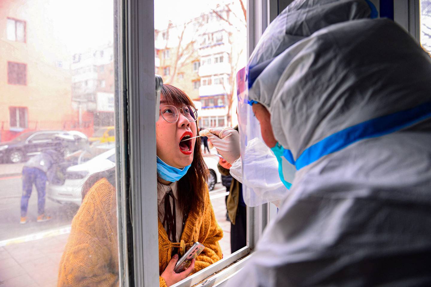 A resident (L) undergoes a nucleic acid test for the Covid-19 coronavirus in Shenyang in China's northeastern Liaoning province on March 9, 2022.  (Photo by AFP)  /  China OUT