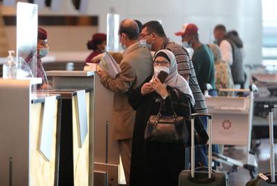Travellers wait at the Qatar Airways check-in desk ahead of a flight at Hamad International Airport near the Qatari capital Doha on January 18, 2021. AFP