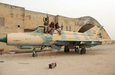 Members of Al-Qaeda's Syrian affiliate and its allies sit on top of a former Syrian army MiG-21 figther jet after they seized the Abu Duhur military airport, the last regime-held military base in northwestern Idlib province on September 9, 2015 in the latest setback for President Bashar al-Assad's forces. Al-Nusra Front and a coalition of mostly Islamist groups captured the military airport after a siege that lasted two years, the Syrian Observatory for Human Rights monitor said. AFP PHOTO / OMAR HAJ KADOUR (Photo by OMAR HAJ KADOUR / AFP)