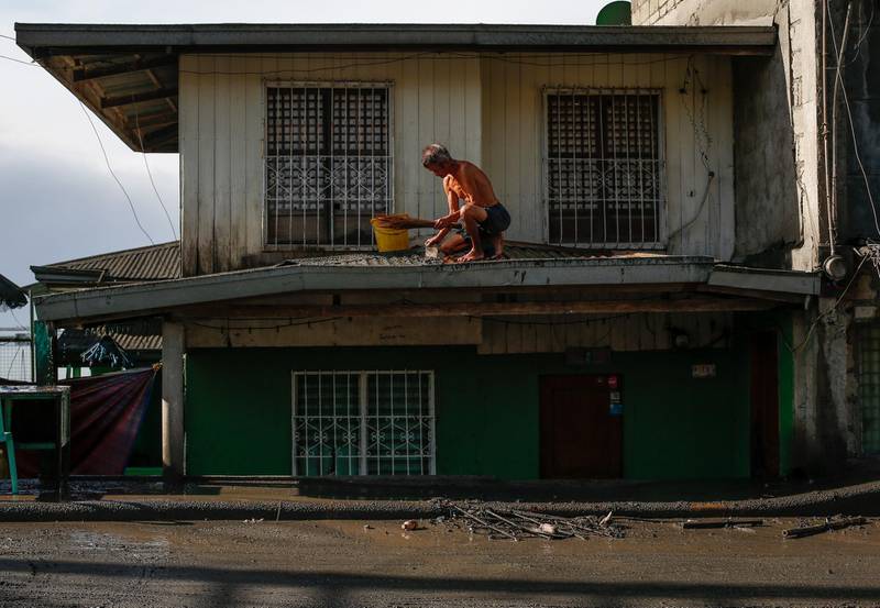 A man cleans a roof after a volcano eruption in Talisay, Batangas. EPA