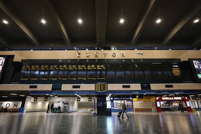 A traveller walks under the departures board of an empty Euston Station in London, as rail workers strike. Getty Images