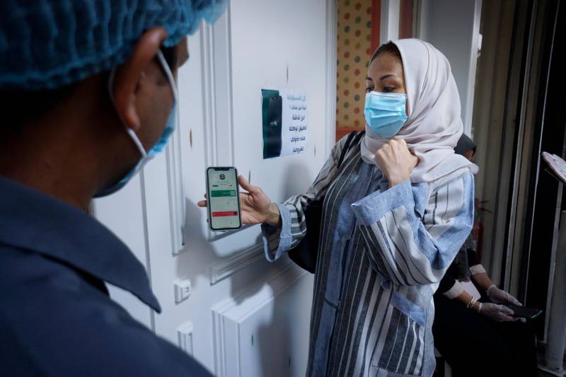 Saudi woman Hala Abdullah shows her details on the Tawakkalna app, launched by Saudi authorities last year to track coronavirus infections, as she enters a shop in Jeddah, Saudi Arabia. Restrictions have been tightened recently, following a spike in cases. AP Photo