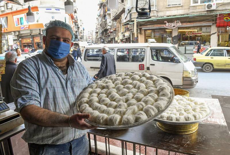 A shopkeeper displays trays of pistachio-filled candy floss rolls at a confectionery as people shop ahead of the start of Ramadan, in northern Syrian city of Aleppo. AFP
