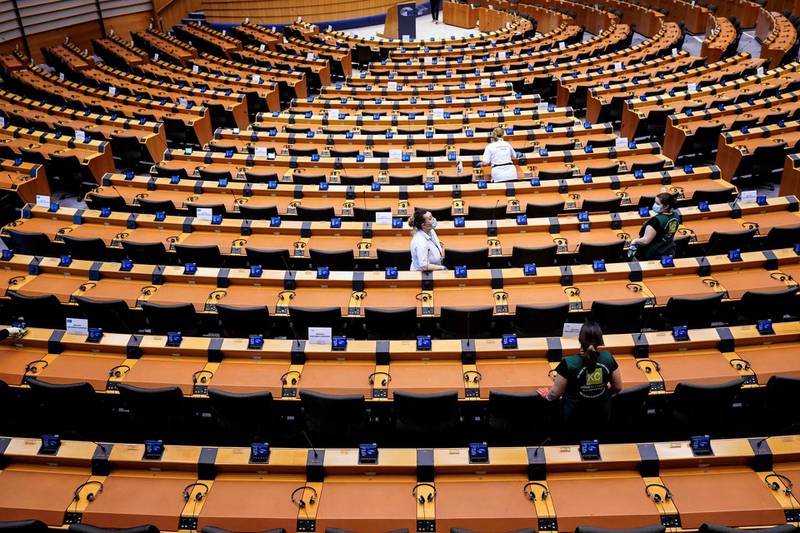 Members of a sanitising crew clean the hemicycle ahead to plenary session of the European Parliament in Brussels on May 27, 2020.  The EU is sinking into the worst recession in its history but -- unlike the US or China -- has no plan yet to relaunch the economy, bogged down by member-state bickering. / AFP / Kenzo TRIBOUILLARD
